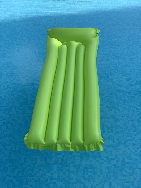 groene opblaasbare matras drijvend op het wateroppervlak - Foto, afbeelding