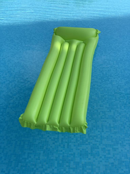 colchón inflable verde flotando en la superficie del agua
 - Foto, imagen