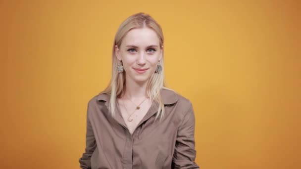 menina loira em blusa marrom sobre fundo laranja isolado mostra emoções
 - Filmagem, Vídeo
