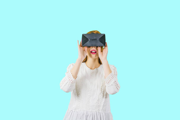Attracting a young woman in a white blouse with a VR headdress, a shocking look of panic on isolates screen - Φωτογραφία, εικόνα