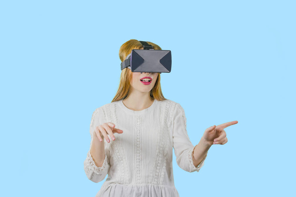 An imaginary game in 3D glasses, a young cute girl with long red hair in 3D glasses, which is turned on imaginary, a photo on an isolated background - Foto, imagen