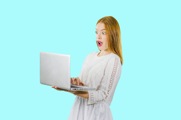 Young woman holding mouth wide open, looking surprised, spreading hands working on laptop pc computer isolated on blue. People sincere emotions lifestyle concept. - Fotografie, Obrázek