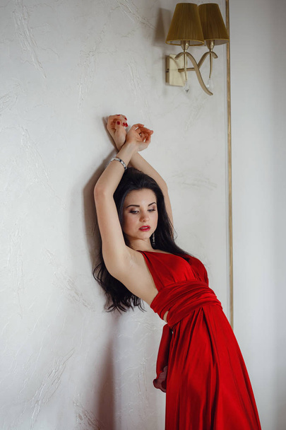 Όμορφη σέξι γυναίκα με κόκκινο φόρεμα που αναζητούν χαρούμενο ποζάρισμα. - Φωτογραφία, εικόνα