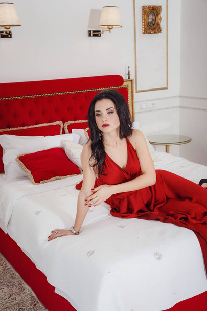 alluring woman in red dress relaxing on a sofa in luxury interior - Zdjęcie, obraz
