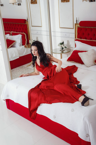 alluring woman in red dress relaxing on a sofa in luxury interior - Photo, image