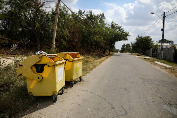 Gelbe Plastikmülltonnen auf einer Dorfstraße, in der niemand herumläuft  - Foto, Bild