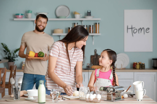 Молодая семья готовит вместе на кухне
 - Фото, изображение