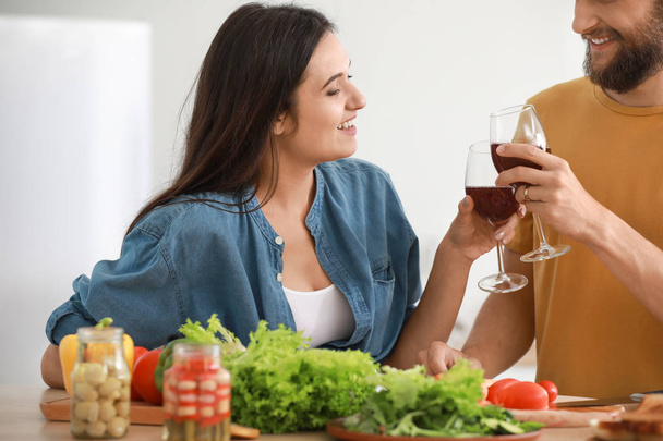 Jeune couple boire du vin tout en cuisinant ensemble dans la cuisine
 - Photo, image