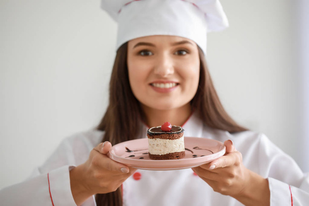 Beautiful female chef with tasty cake in kitchen - Photo, image