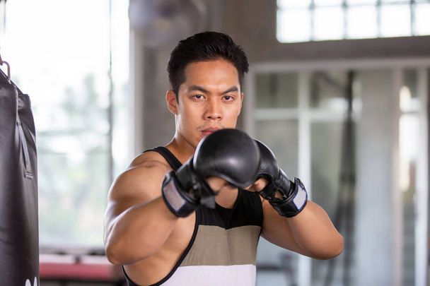 Concept de combat de boxe, Sac de boxe hispanique homme dans le gymnase, Jeune homme boxe en utilisant un sac de boxe dans le gymnase
 - Photo, image