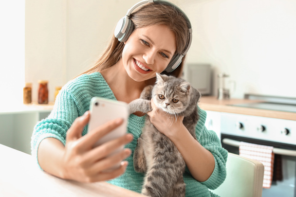 Beautiful young woman taking selfie with cute cat in kitchen - Foto, immagini