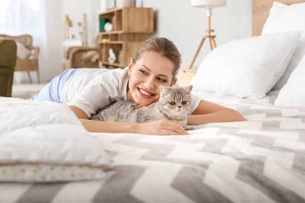 Beautiful young woman with cute cat in bedroom - Valokuva, kuva