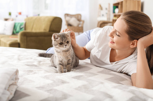 Beautiful young woman with cute cat in bedroom - 写真・画像