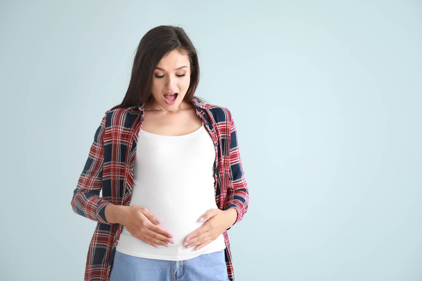 Surprised pregnant woman on color background - Photo, Image