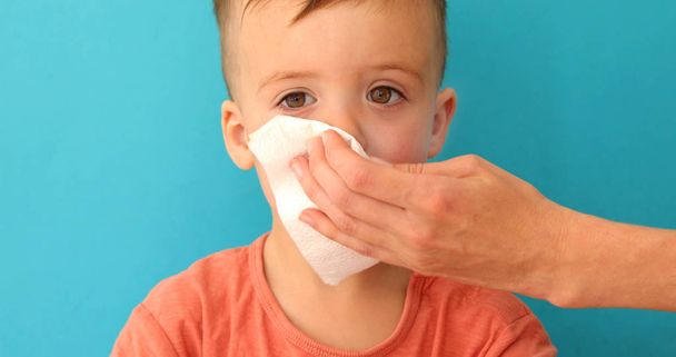 Adulto ajuda criança a soprar e limpar seu nariz correndo
 - Foto, Imagem