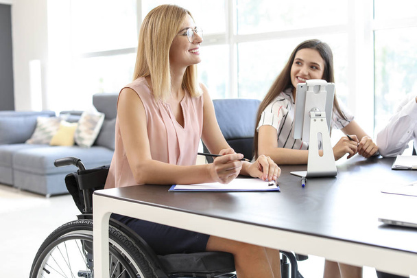 Handicapped young woman with colleagues working in office - Foto, Imagen