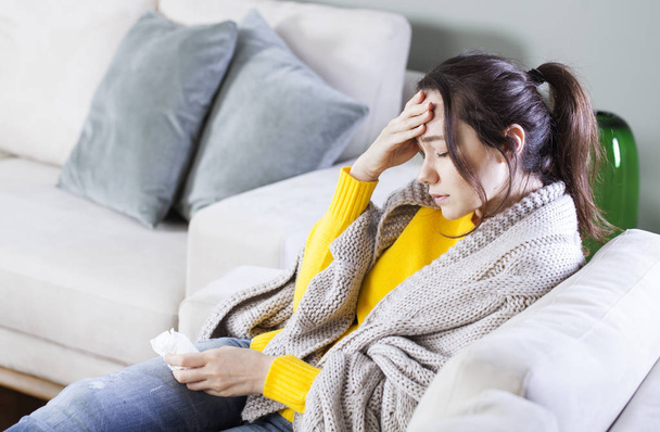Young woman with headache sitting on sofa - Photo, Image