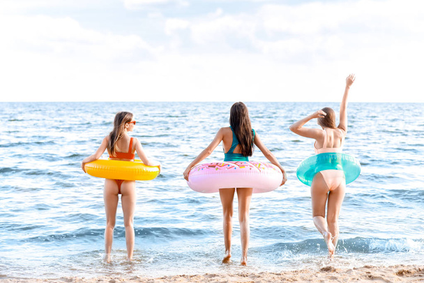 リゾートで海のビーチで水泳リングを持つ美しい若い女性 - 写真・画像