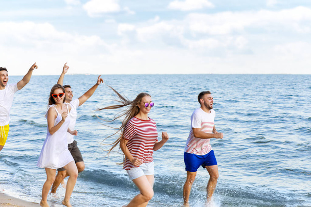 Amigos felices corriendo en la playa del mar en el resort
 - Foto, imagen