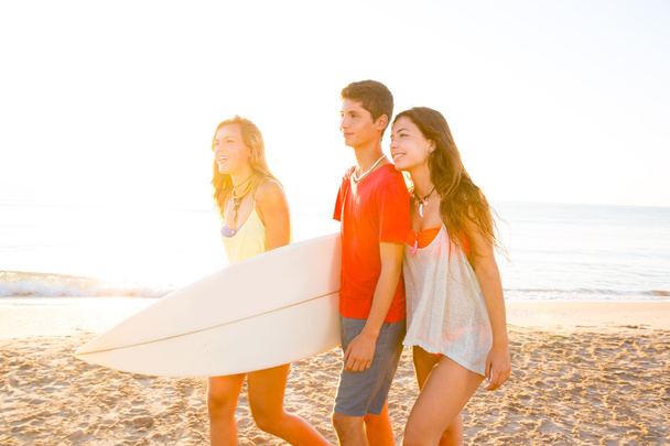 Surfer girls with teen boy walking on beach shore - Foto, imagen