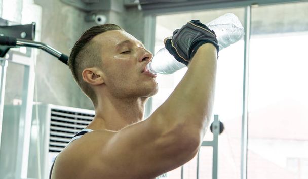 vista laterale dell'uomo che beve acqua dopo l'esercizio in palestra
 - Foto, immagini