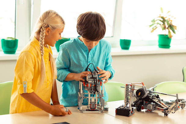 Girl and boy constructing a small robot together. - Фото, зображення