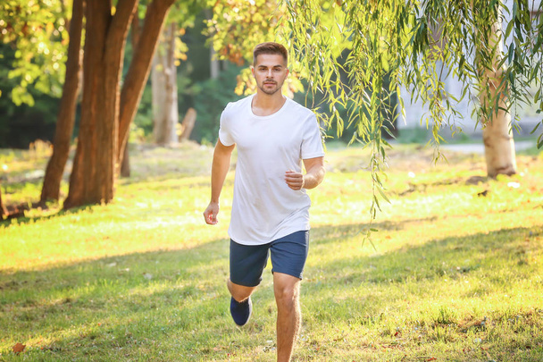 Komea urheilullinen mies juoksee puistossa
 - Valokuva, kuva