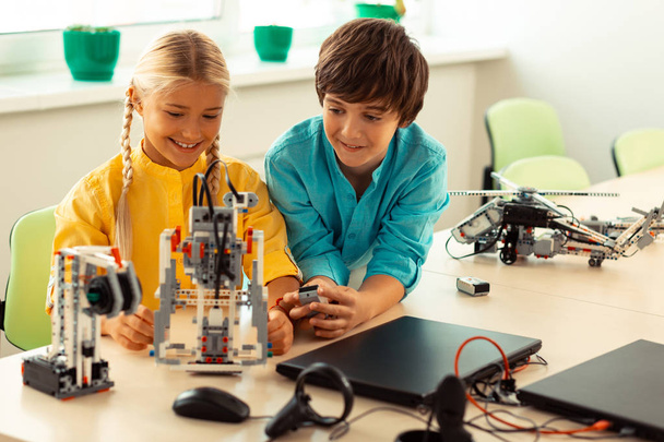 Boy helping his classmate turning on a robot. - Foto, afbeelding
