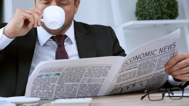 επιχειρηματίας να διαβάζει οικονομικές εφημερίδες και να πίνει καφέ στο γραφείο - Πλάνα, βίντεο