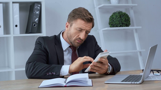 hombre de negocios maduro utilizando la calculadora y la escritura en cuaderno en la oficina
 - Imágenes, Vídeo