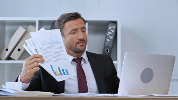 ofiste dizüstü bilgisayarda görüntülü sohbet sırasında kağıtları gösteren olgun işadamı - Video, Çekim