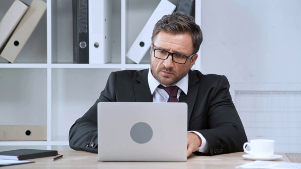 mature businessman putting glasses and using laptop - Filmati, video