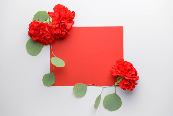 Beautiful carnation flowers and blank card on light background - Photo, Image
