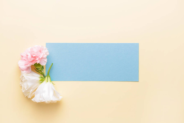 Mooie bloemen en blanco kaart op kleur achtergrond - Foto, afbeelding