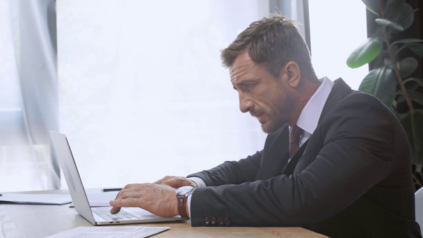 side view of mature businessman typing on laptop - Video, Çekim