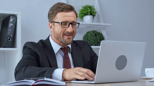 homme d'affaires mature dans des lunettes à l'aide d'un ordinateur portable et montrant geste ouais
 - Séquence, vidéo