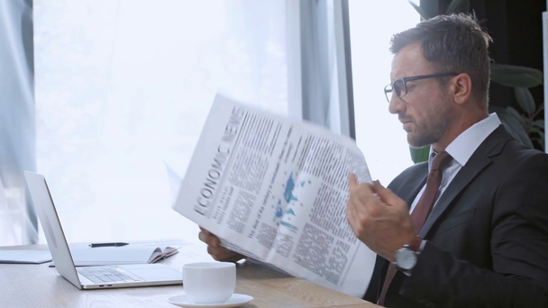 hombre de negocios maduro usando el ordenador portátil y leyendo el periódico
 - Metraje, vídeo