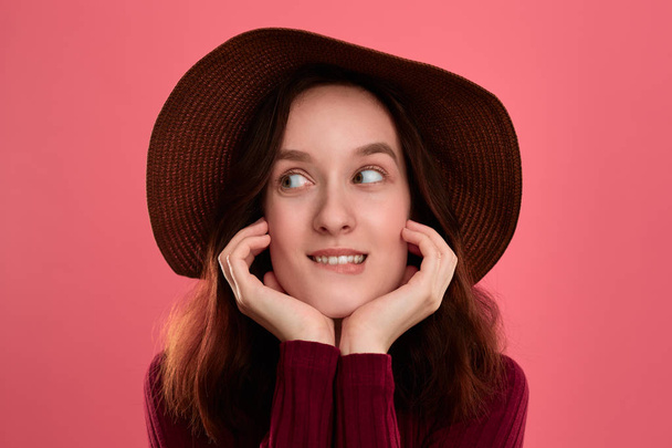 Podrobný portrét šťastné a krásné brunety v klobouku s širokým brkem a Pózované na tmavě růžovém pozadí. - Fotografie, Obrázek
