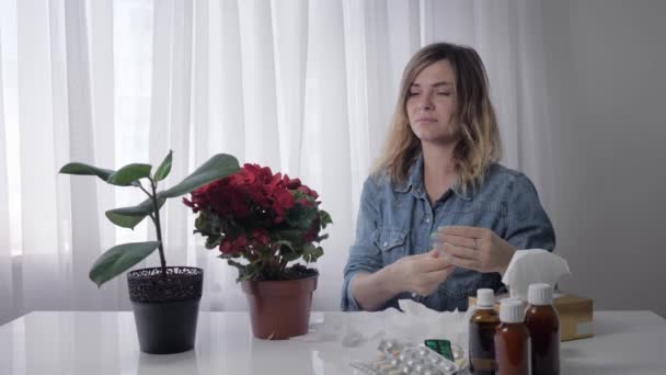 Alergia oddechowa, młoda kobieta cierpi na kichanie i przyjmuje leki przeciwhistaminowe, aby czuć się lepiej w jasnym pomieszczeniu - Materiał filmowy, wideo