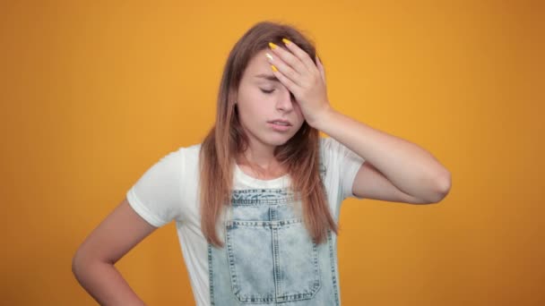 Молода жінка в білій футболці на помаранчевому фоні показує емоції
 - Кадри, відео