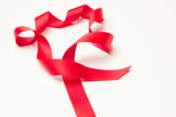 rood lint om decoratieve banden te maken in de giften van Kerstmis, verjaardagsgiften, jubilea, giften in het algemeen; rood lint op witte achtergrond - Foto, afbeelding
