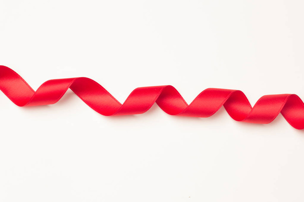 красная лента, чтобы сделать декоративные галстуки в рождественские подарки, подарки ко дню рождения, юбилеи, подарки в целом; красная лента на белом фоне
 - Фото, изображение