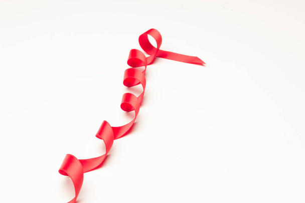 cinta roja para hacer lazos decorativos en regalos de Navidad, regalos de cumpleaños, aniversarios, regalos en general; cinta roja sobre fondo blanco
 - Foto, Imagen