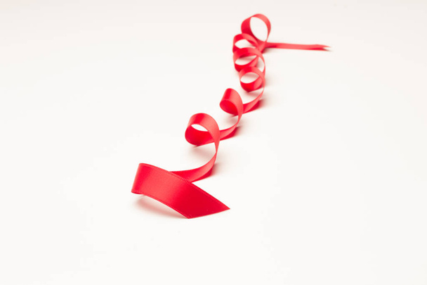 クリスマスプレゼント、誕生日プレゼント、記念日、一般的な贈り物で装飾的なネクタイを作るために赤いリボン。白い背景に赤いリボン - 写真・画像