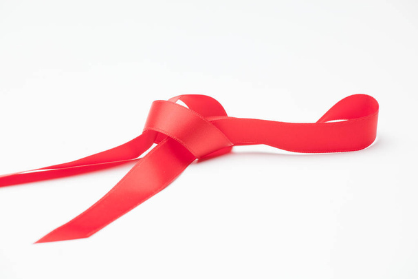 красная лента, чтобы сделать декоративные галстуки в рождественские подарки, подарки ко дню рождения, юбилеи, подарки в целом; красная лента на белом фоне
 - Фото, изображение