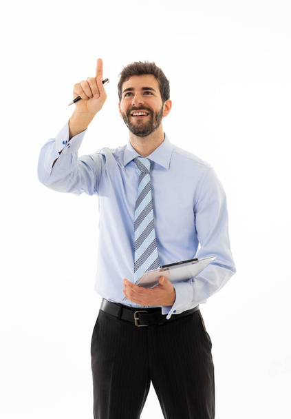 Young attractive businessman pointing at copy space as using a virtual screen. Smiling feeling confident and successful. In people business education, success and new technology at work concept. - Photo, Image