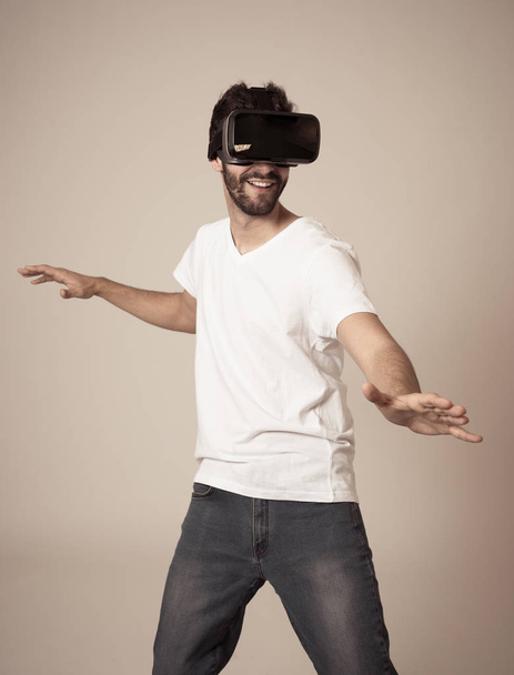 Casual bearded young man using VR headset glasses goggles feeling excited trying simulation, exploring virtual reality making gestures interacting with new 3D world. In new technology concept. - Foto, Imagem