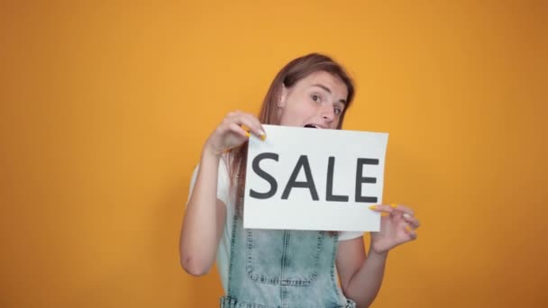 Young woman wearing white t-shirt, over orange background shows emotions - Filmmaterial, Video