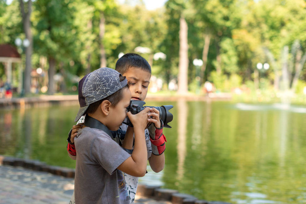 二人の少年が湖のそばに立って、パで自然の写真を撮ります - 写真・画像