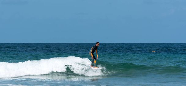 Een atletische man surfen golven in de Atlantische Oceaan aan de kust van Bretagne op een zomerdag - Foto, afbeelding